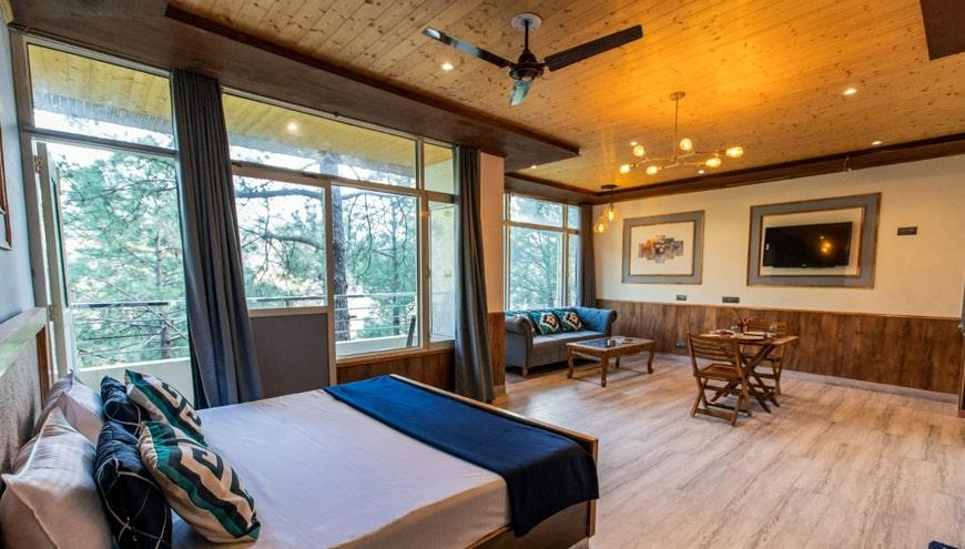 a bedroom with a large bed and sofa at pinewood nirvana shoghi in shimla hotel_Image