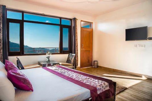 a bedroom with window view and chairs at shimla nature ville in shimla hotel_Image