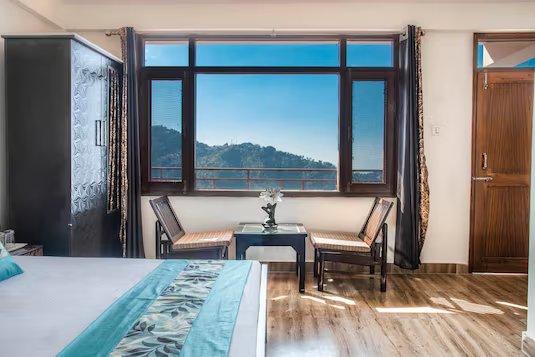 a bedroom with window view and chairs at shimla nature ville in shimla hotel_Image
