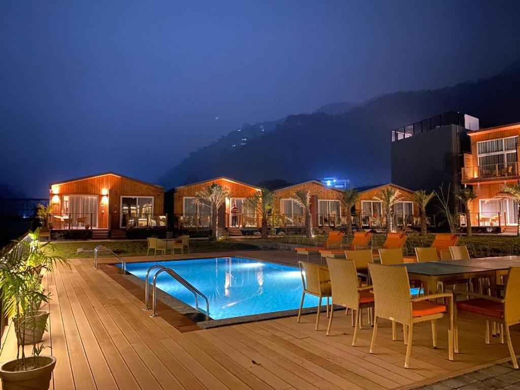 a front view of hotel with swimming pool and chairs at sukham raasa river in rishikesh hotel_Image