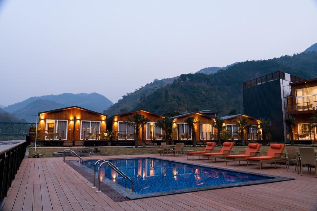 a front view of hotel with swimming pool and chairs at sukham raasa river in rishikesh hotel_Image