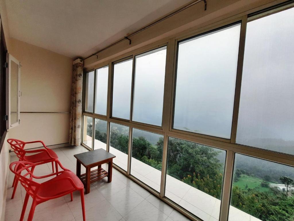 a balcony with chair and table and a view of the mountains at sunrise villa in shimla hotel_Image