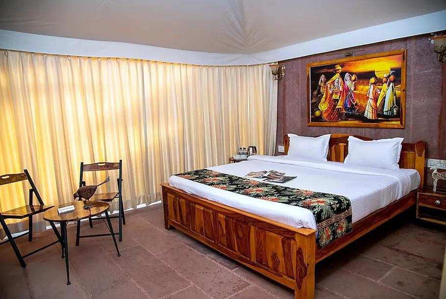 a bedroom with a large bed and chair at kurja resort in jodhpur hotel_Image