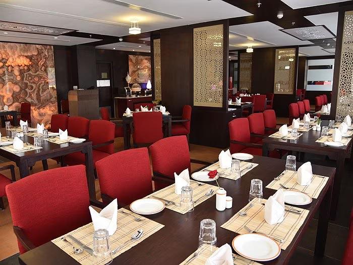 a hotel restaurants with chair sofa & wooden table at vesta grand central udaipur hotel_Image